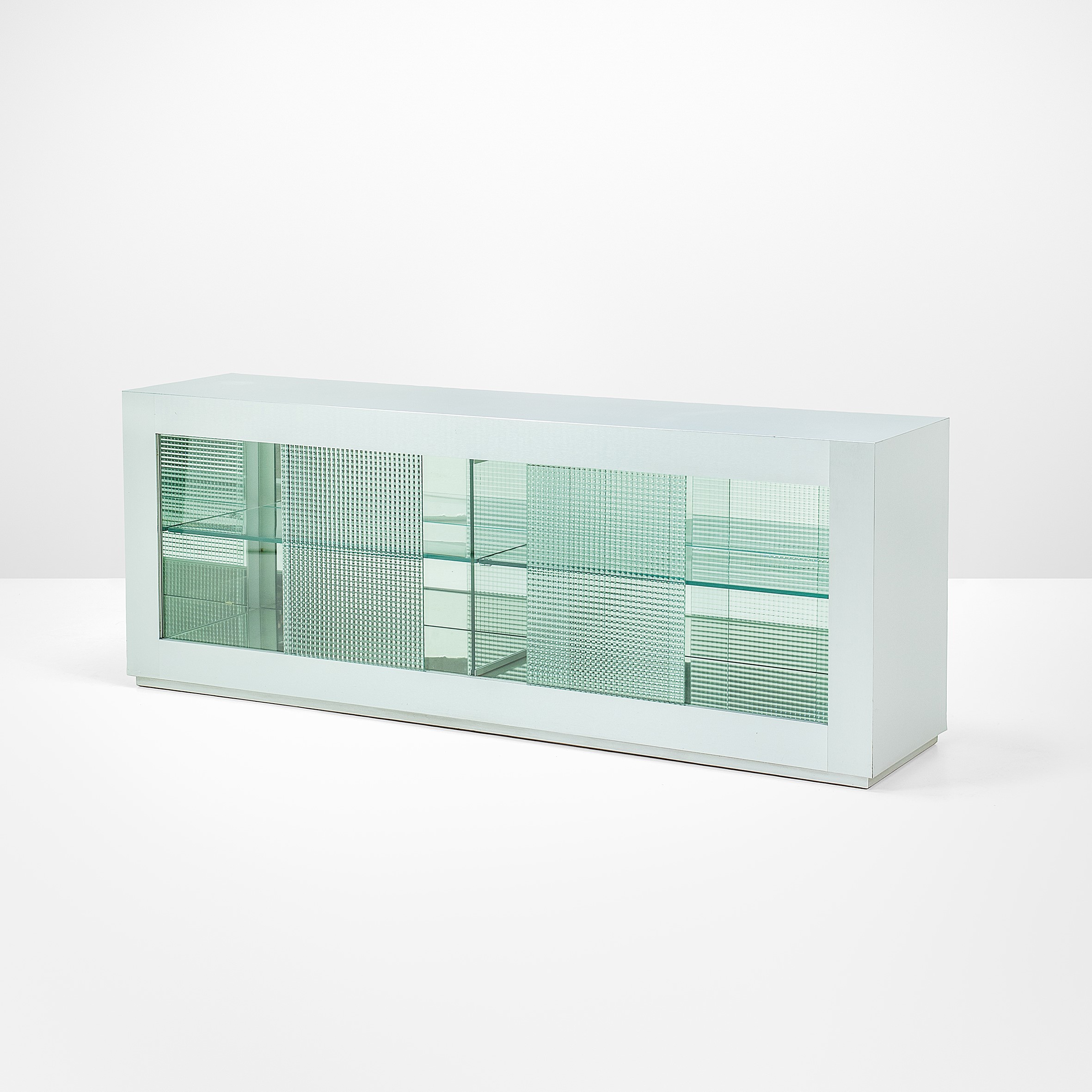 Una credenza bianca minimalista con una combinazione di ante in vetro pieno e decorato, dotata di due ripiani interni in vetro, posizionati su uno sfondo bianco semplice.