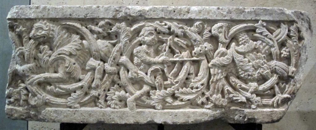 Antico rilievo in pietra con intricate incisioni di figure umane, creature mitologiche, viticci e motivi floreali, che mette in mostra la maestria artigianale e il design artistico.