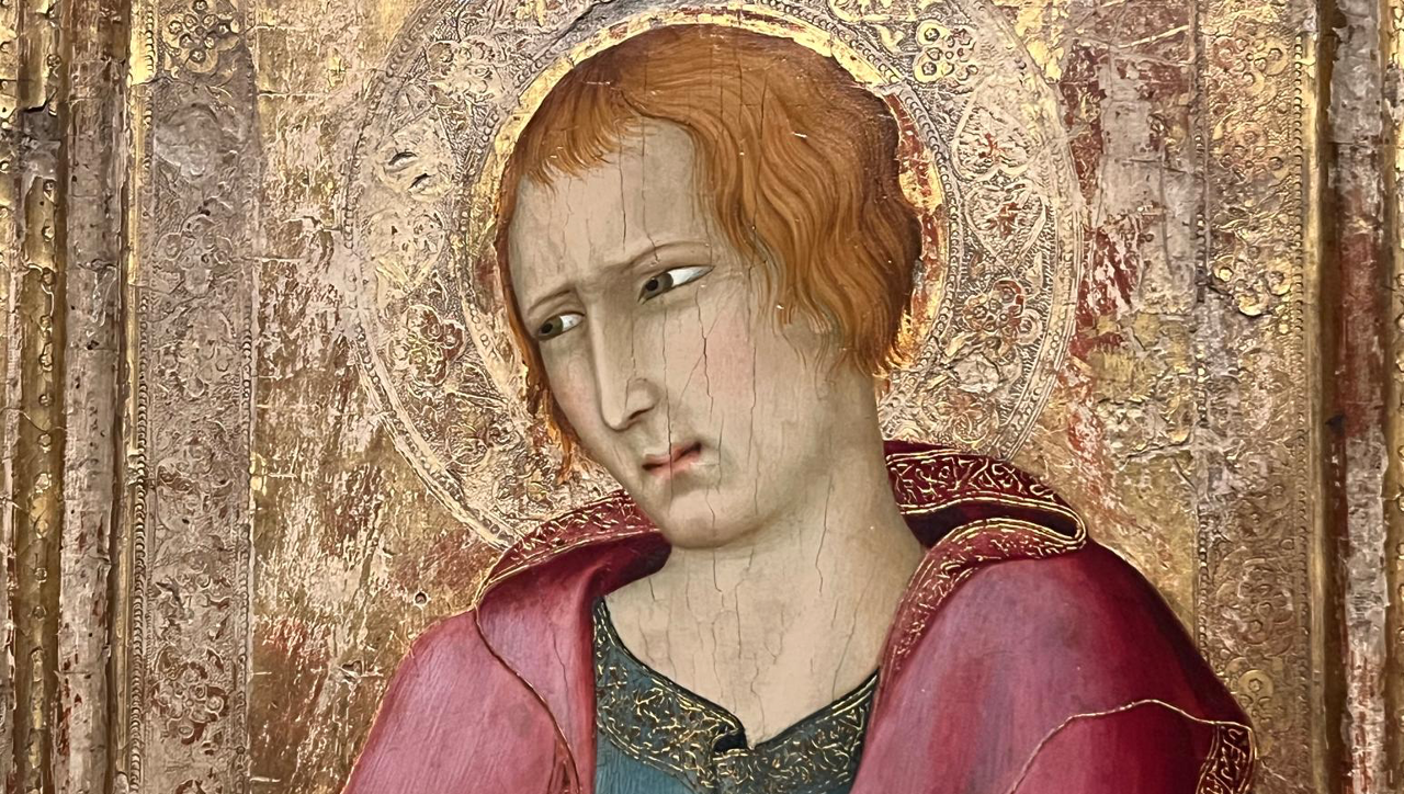 Un dipinto in stile medievale raffigura una figura con un'espressione solenne. La figura ha capelli corti e ondulati e indossa una tunica rossa e oro con un intricato disegno di alone sullo sfondo. L'opera d'arte presenta dettagli ornati e superfici strutturate.