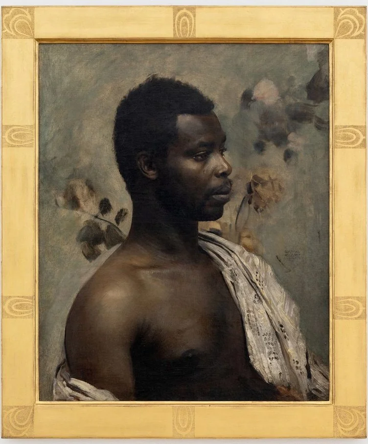Ritratto di un uomo con corti capelli neri, rivolto a sinistra, che indossa un panno bianco drappeggiato su una spalla. I motivi floreali tenui sullo sfondo aggiungono eleganza, mentre la cornice gialla decorativa del dipinto richiama la raffinatezza spesso vista nelle mostre TEFAF.