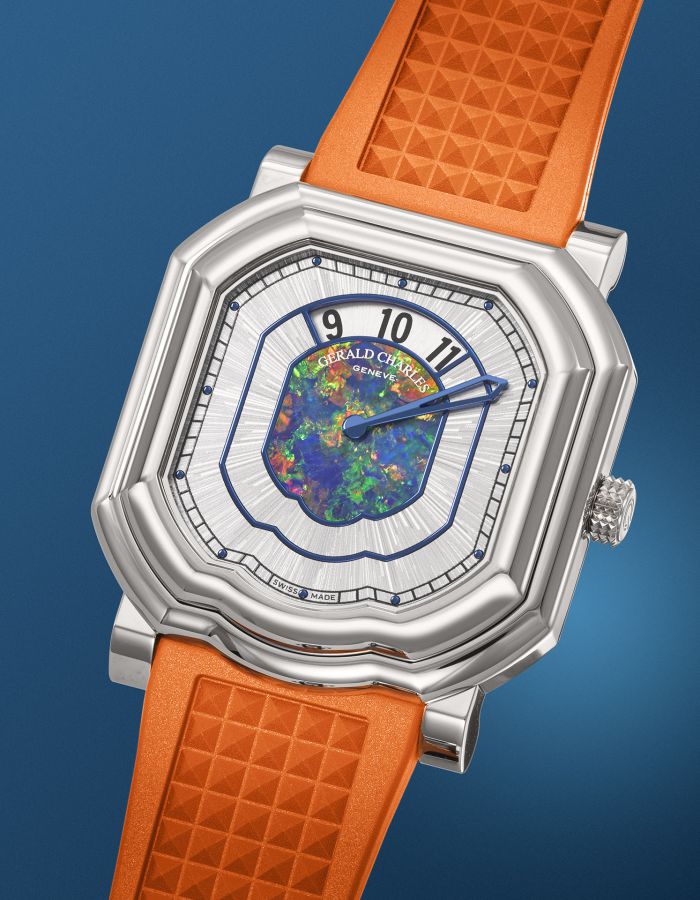 Un orologio da polso di lusso con cassa quadrata in argento, quadrante con motivo opalino blu e verde, numeri neri e cinturino in gomma testurizzata arancione, su uno sfondo blu, che ricorda lo stile audace degli orologi Richard Mille Nadal.