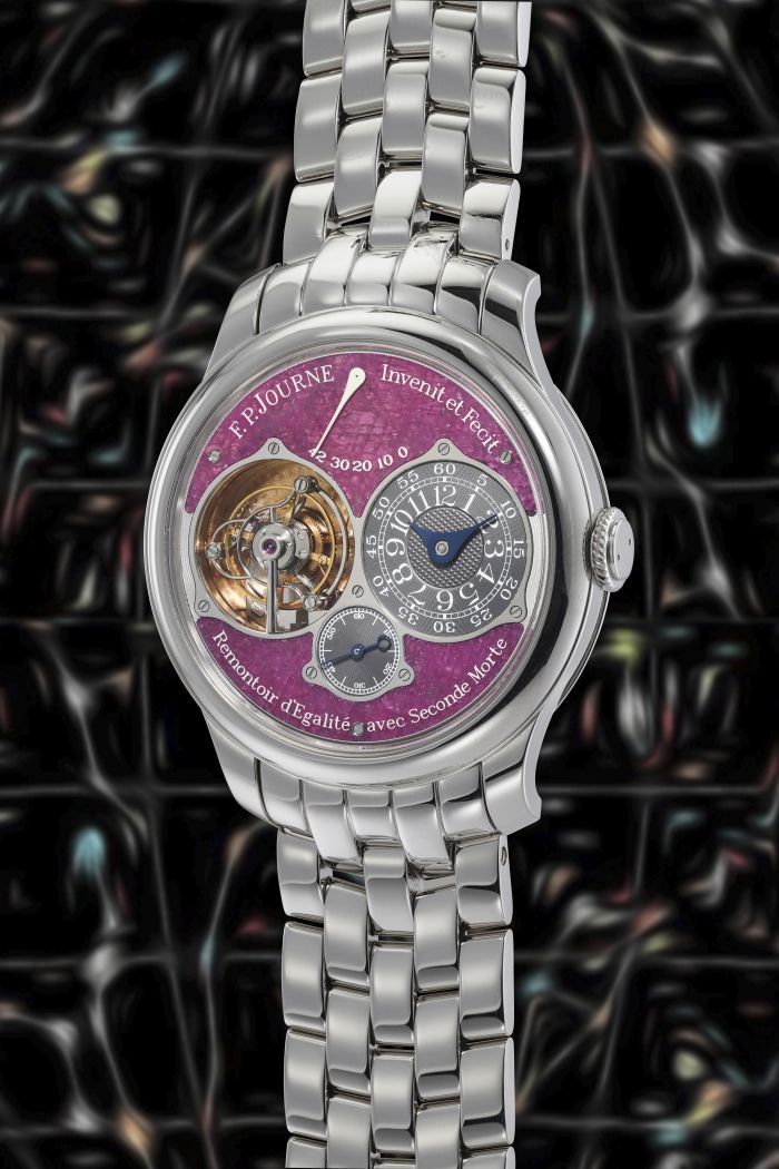 Un lussuoso orologio da polso F.P. Journe con cinturino in metallo argentato, meccanismo tourbillon aperto e quadrante con dettagli viola, su uno sfondo scuro con motivo astratto: un'icona tra gli orologi lusso nuove tendenze.