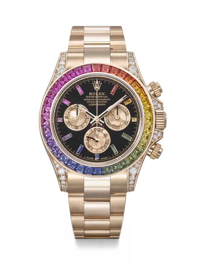 Un Rolex in oro con quadrante nero, tre contatori e lunetta incastonata con gemme multicolori a formare un motivo arcobaleno. Presentato a un'asta di Christie's dedicata agli orologi, il suo cinturino in oro e le anse con diamanti trasudano lusso.