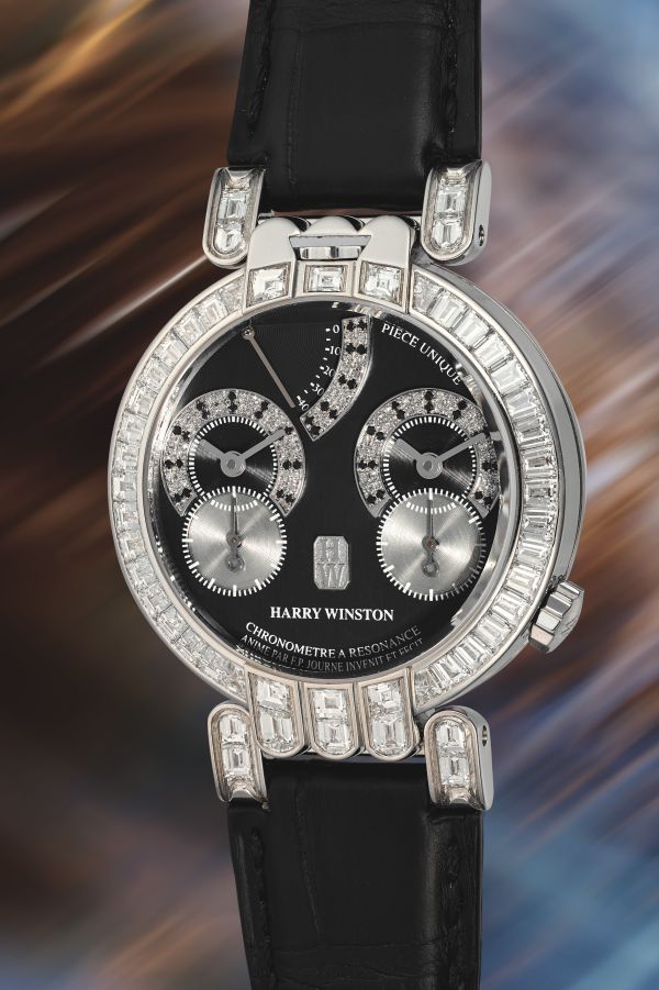 Un lussuoso orologio Harry Winston con cinturino in pelle nera, quadrante nero, quadranti multipli e cassa impreziosita da grandi diamanti scintillanti evoca il prestigio spesso visibile alle aste Patek Philippe Phillips, su uno sfondo sfocato e multicolore.