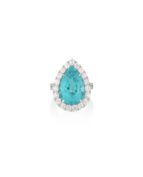 Un anello con pietra preziosa blu a forma di pera è incastonato in un alone di diamanti bianchi rotondi su una fascia d'argento, che ricorda l'eleganza dell'Orologio Bulgari Serpente, e presentato su uno sfondo bianco.