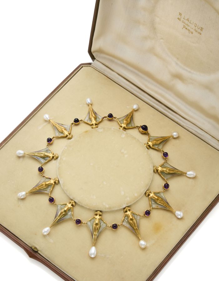 Collana in oro con pietre preziose di ametista e gocce di perle, esposta in un cofanetto portagioie aperto e foderato di velluto con la scritta "Lalique, Paris". La collana presenta segmenti decorati a forma di ventaglio.