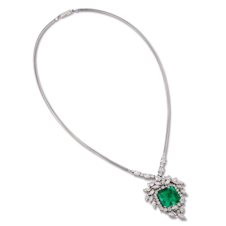 Una collana in argento con un grande pendente con pietra preziosa verde quadrata, circondato da scintillanti diamanti bianchi di varie forme e dimensioni: un design ispirato alla raffinata eleganza del Patek Philippe Nautilus Asta.