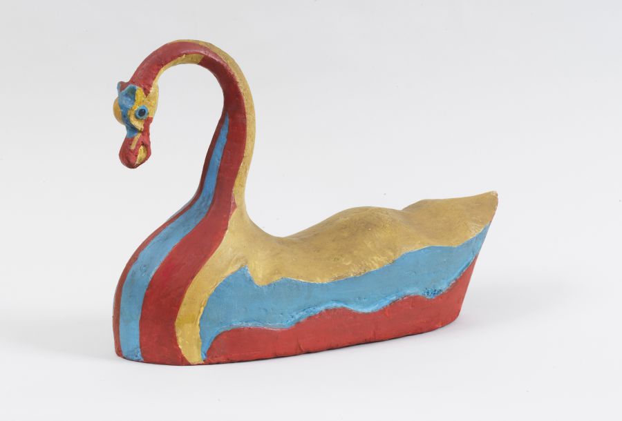 Una scultura colorata di un cigno dal collo lungo e ricurvo, dipinta in rosso, blu e oro su un semplice sfondo bianco. Lo stile elegante del cigno evoca la maestria artistica vista alla Triennale di Gucci.