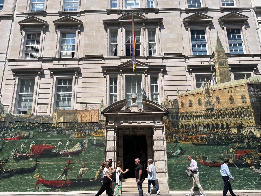 La facciata dell'edificio è decorata con un elaborato murale nello stile del Canaletto che raffigura gondole veneziane sull'acqua; le persone camminano sul marciapiede e una bandiera arcobaleno è esposta sopra l'ingresso, evocando una vivace scena di asta del Canaletto.