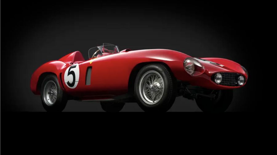 Una classica auto da corsa rossa con un prominente cerchio bianco e il numero 5 nero sulla fiancata, cerchi a raggi argentati, abitacolo scoperto e carrozzeria elegante e curva, esposta su uno sfondo nero: un omaggio alla Mille Miglia 2025.