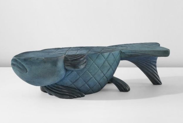 Una panca scolpita a forma di pesce blu con motivi strutturati e squamosi sul corpo, questo design unico Donne Asta è esposto su uno sfondo bianco semplice.