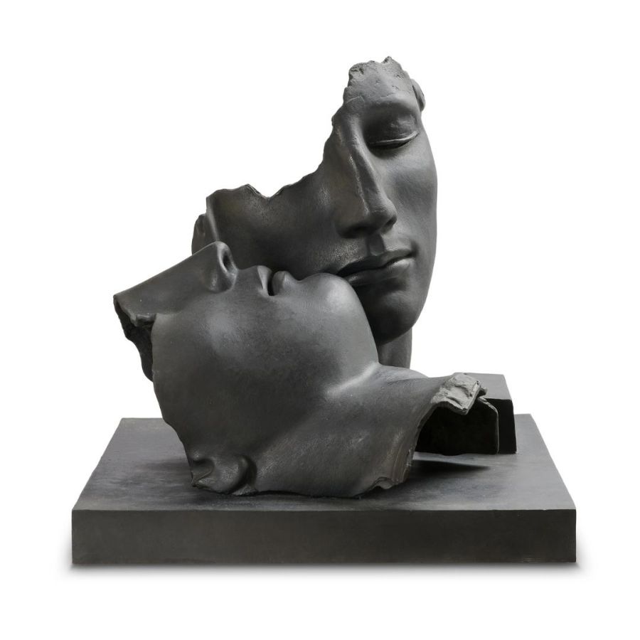 Una scultura in bronzo frammentata di Asta Pandolfini raffigura due volti umani parziali appoggiati l'uno sull'altro su una base rettangolare, con espressioni serene e parti mancanti, creando un senso di intimità e contemplazione.
