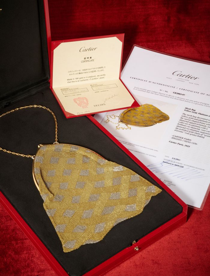 Collana Cartier in maglia d'oro e argento con catena, impreziosita da perle naturali asta, presentata in una scatola Cartier rossa. Sul retro della collana si trovano un certificato di autenticità, un documento Cartier e un'etichetta del prodotto, il tutto su sfondo rosso.