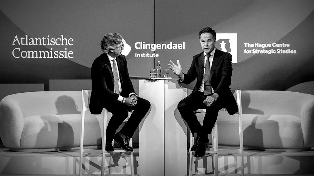 Due uomini in giacca e cravatta siedono sul palco davanti a un tavolo e parlano durante una tavola rotonda. Alle loro spalle, i loghi dell'Atlantische Commissie, del Clingendael Institute e del Centro di studi strategici dell'Aia.