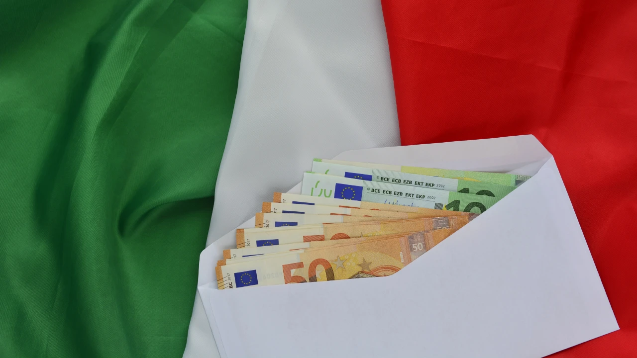 A white envelope containing several euro banknotes is placed over a green, white and red striped Italian flag. The reference is to the topic of financial planning for those retiring in Italy.