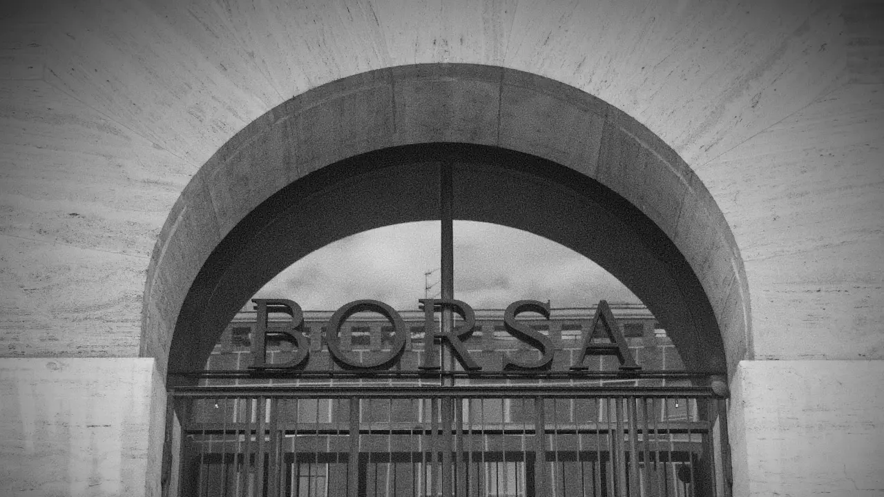 Una foto in bianco e nero mostra un ingresso ad arco con la parola "BORSA" a grandi lettere sopra un cancello di metallo, che riflette un edificio nel vetro dietro di esso.
