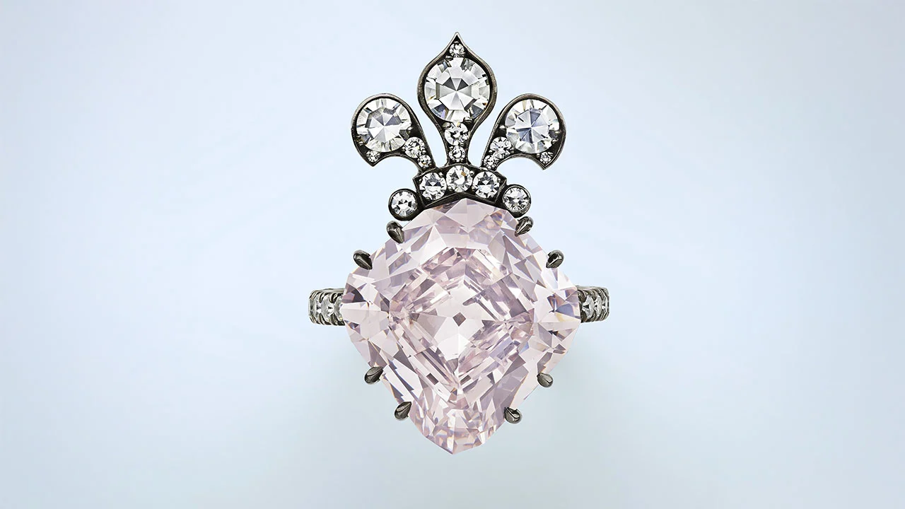 Un anello ornato ispirato a Maria Antonietta, con una grande gemma rosa chiaro al centro, accentuata da pietre bianche più piccole e da un disegno decorativo a forma di corona. La fascia argentata è impreziosita da altre pietre: un pezzo adatto a un'asta da record.
