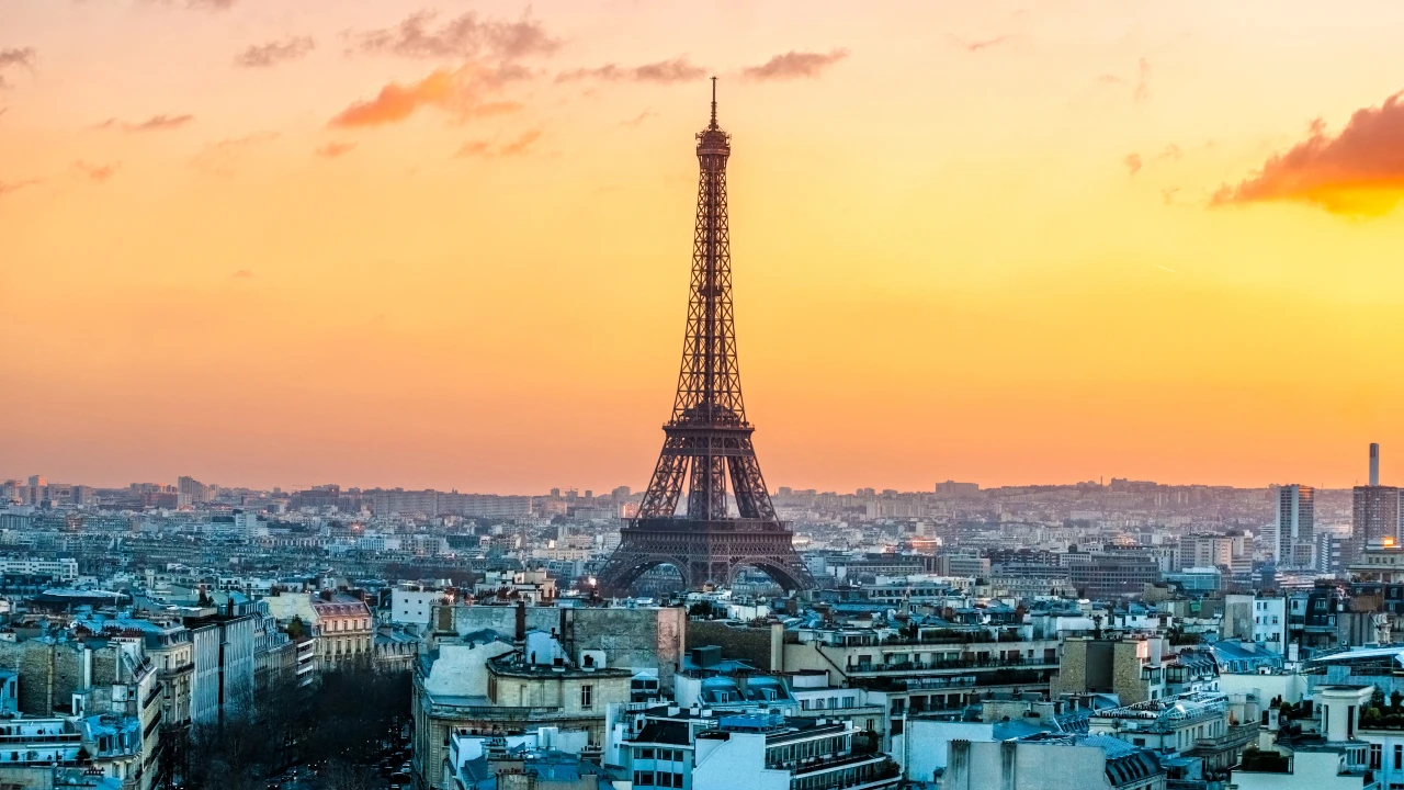 Foto della Torre Eiffel che si erge alta nel centro di Parigi, circondata da edifici cittadini al tramonto. Il riferimento va alla Francia e al modello vincente di affitto ammobiliato in ambito immobiliare.