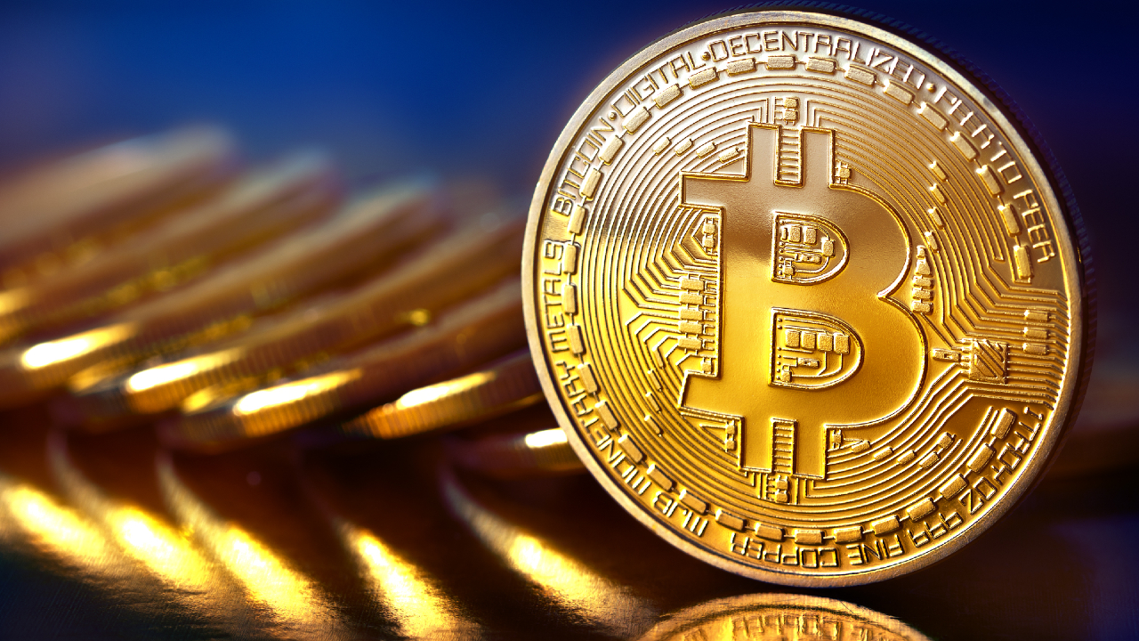 Una moneta fisica color oro lucido con il simbolo del Bitcoin è in piedi, con diverse monete simili sfocate sullo sfondo, a rappresentare le criptovalute e la finanza digitale.