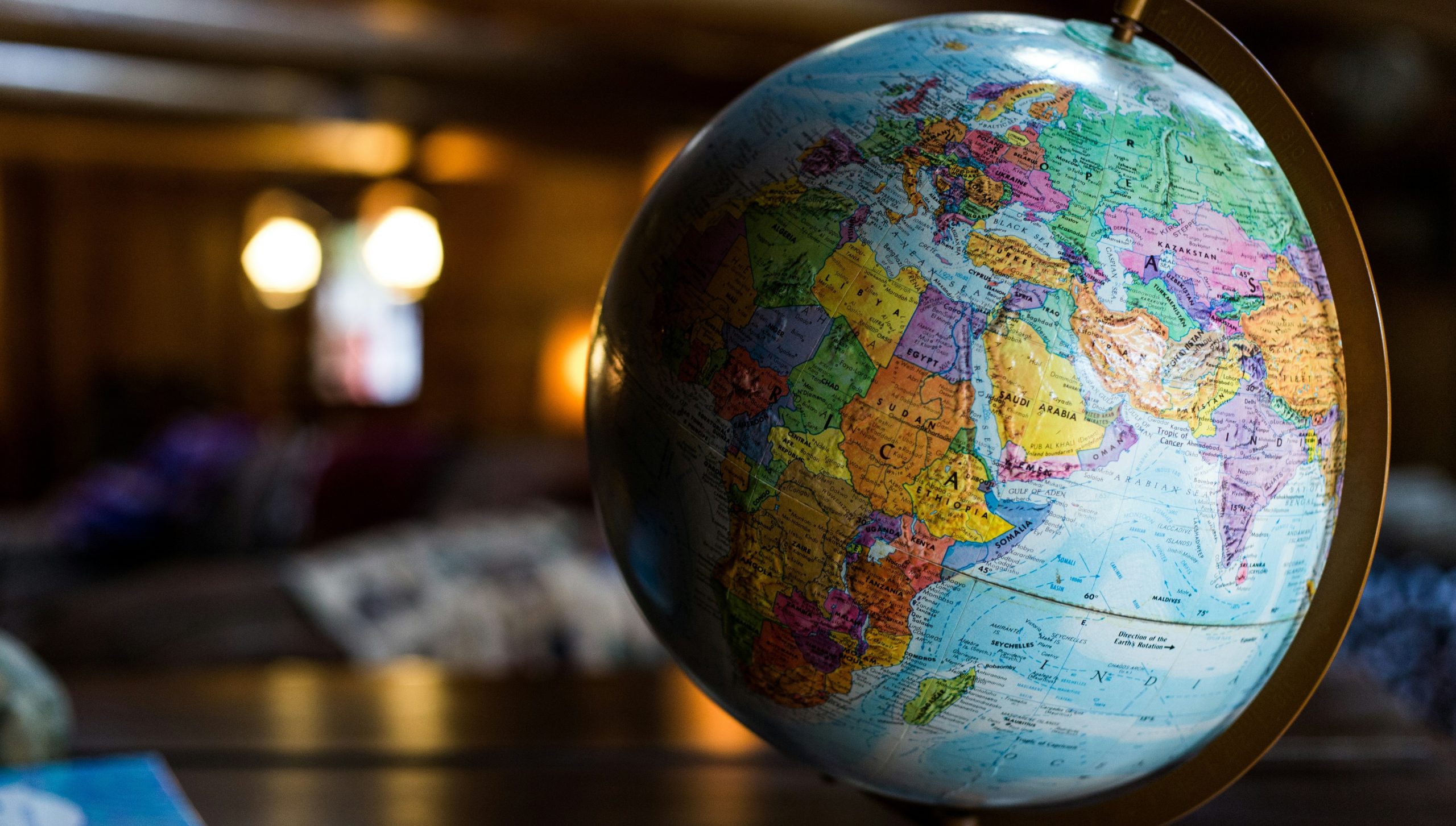 Primo piano di un mappamondo colorato incentrato su Africa, Europa e parte dell'Asia, con uno sfondo interno sfocato e un'illuminazione morbida e calda.