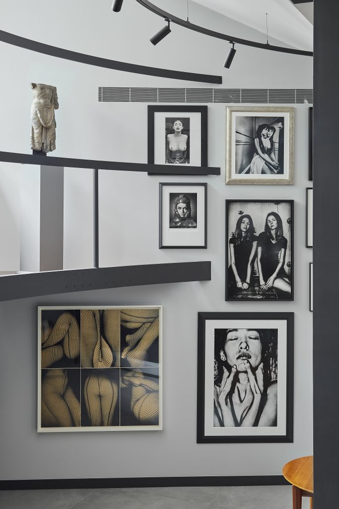 L'interno moderno e minimalista è caratterizzato da una parete grigia ornata da fotografie di persone incorniciate in bianco e nero, da una ringhiera geometrica e da una piccola statua classica, che richiama lo stile raffinato della casa museo Molinario Colombari.
