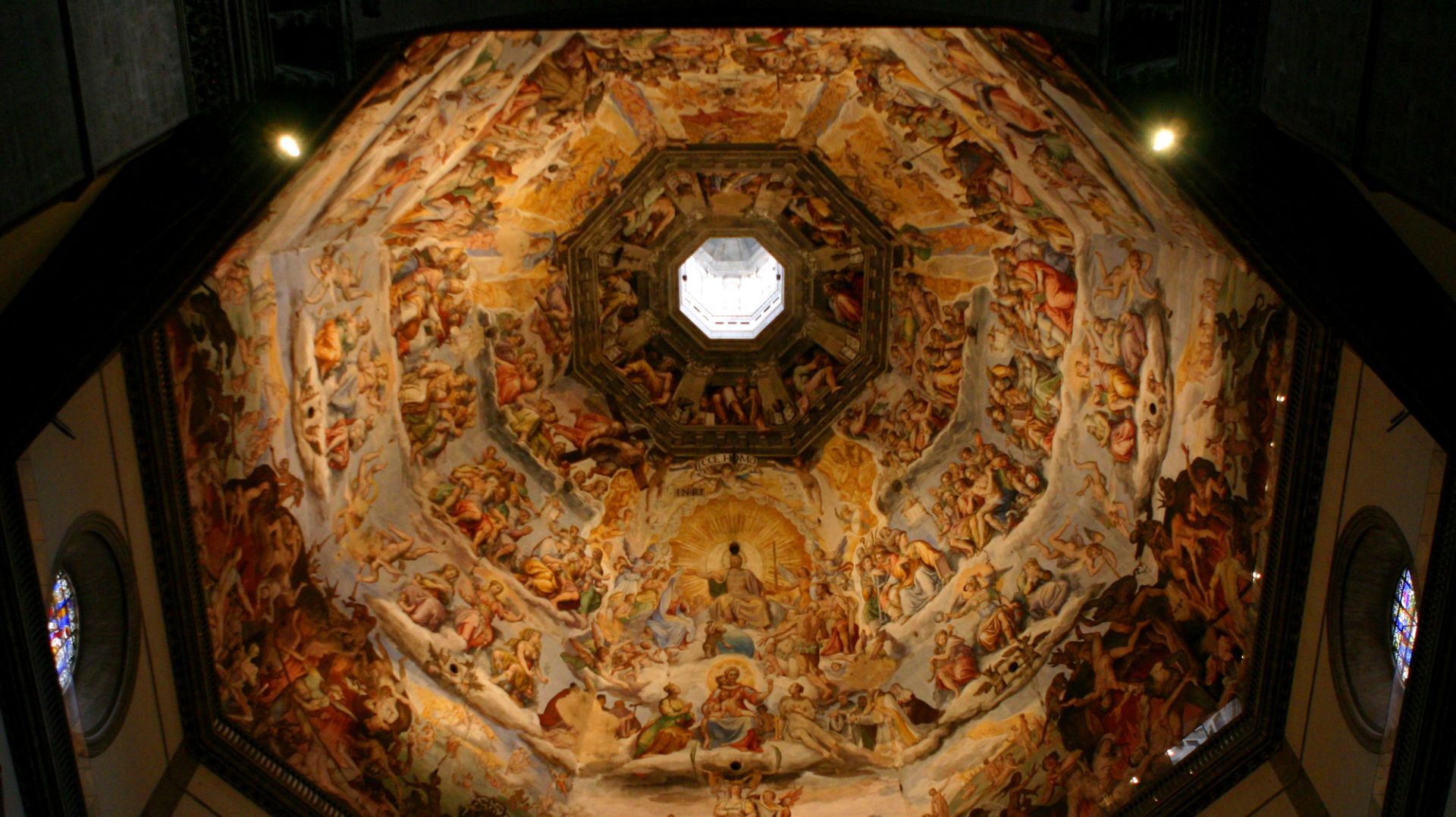 Vista che guarda verso l'alto di un ornato soffitto a cupola ricoperto di vivaci affreschi raffiguranti numerose figure umane, angeli e scene religiose, incentrato su un oculo che lascia entrare la luce naturale.
