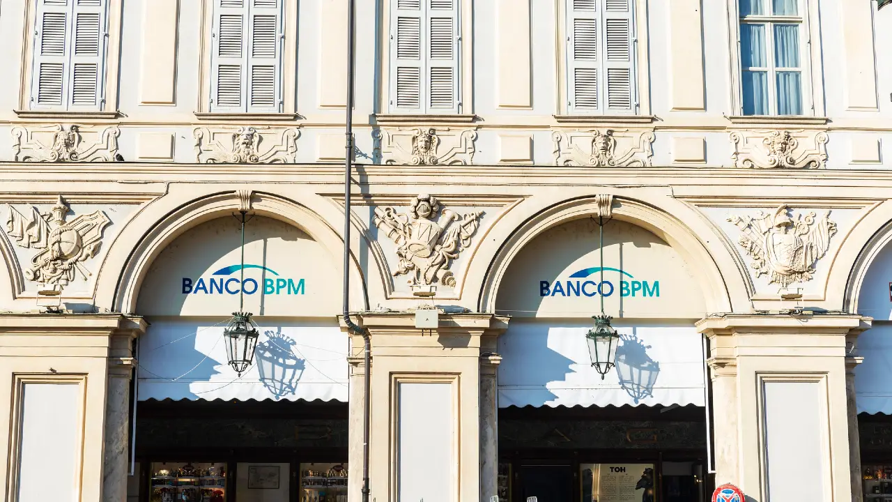 L'esterno di un edificio storico con finestre ad arco con insegne "BANCO BPM", intagli decorativi in pietra e due lanterne sospese.