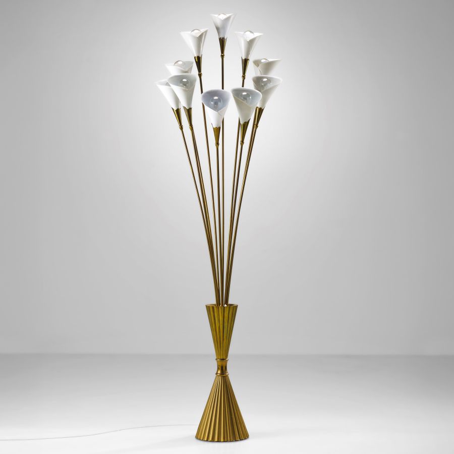 Una lampada da terra color oro con base scanalata, caratterizzata da più steli che si incurvano verso l'alto e sormontati da paralumi bianchi a forma di giglio, mette in mostra un design elegante - di ispirazione settembrina - su uno sfondo grigio semplice.