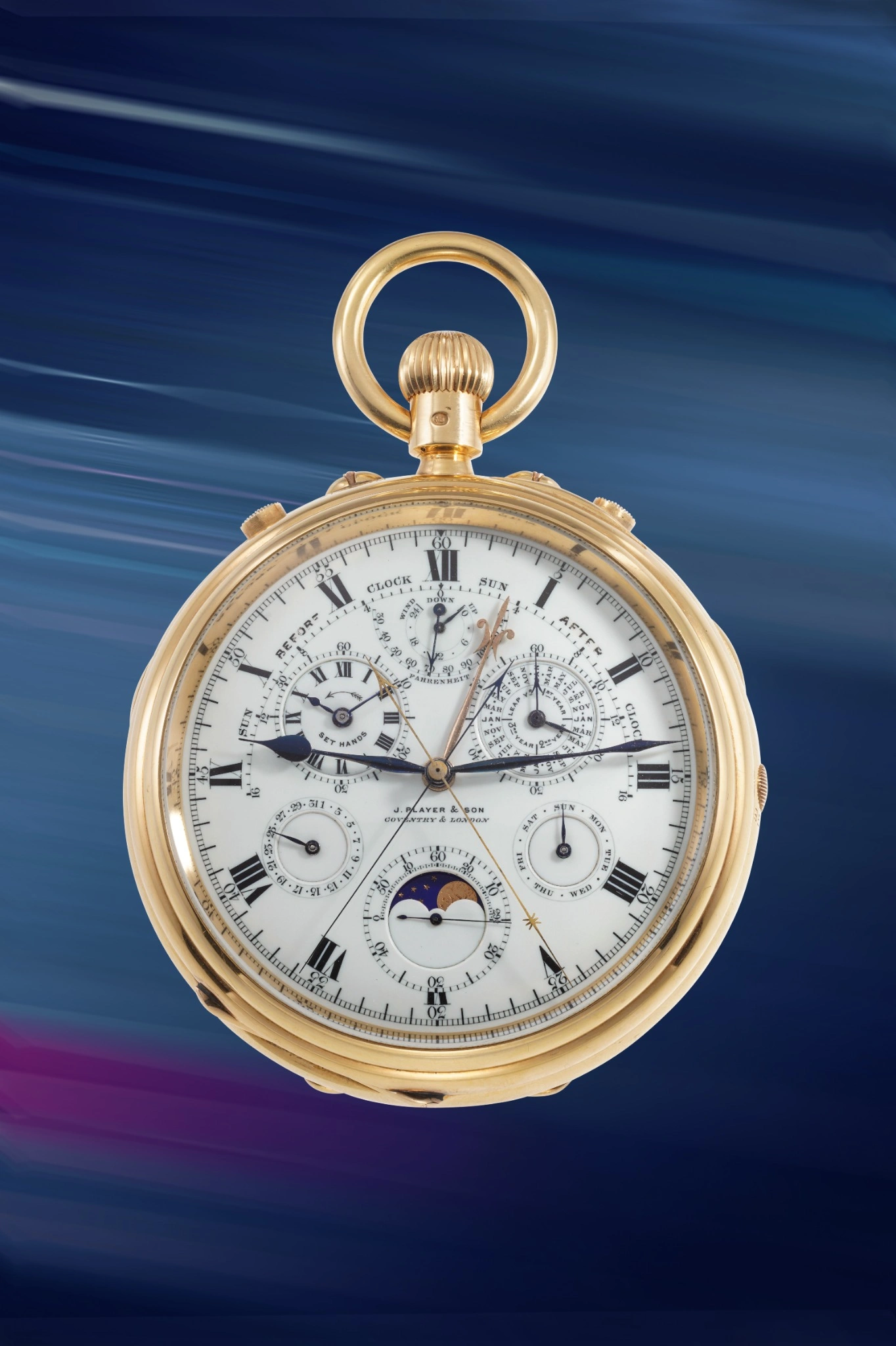 Un orologio da tasca d'oro con quadranti multipli e numeri romani è visualizzato su uno sfondo blu e viola striato, che ricorda i punti salienti dell'asta 10 anni Phillips. L'intricato quadrante presenta contatori, lancette e dettagli del calendario.
