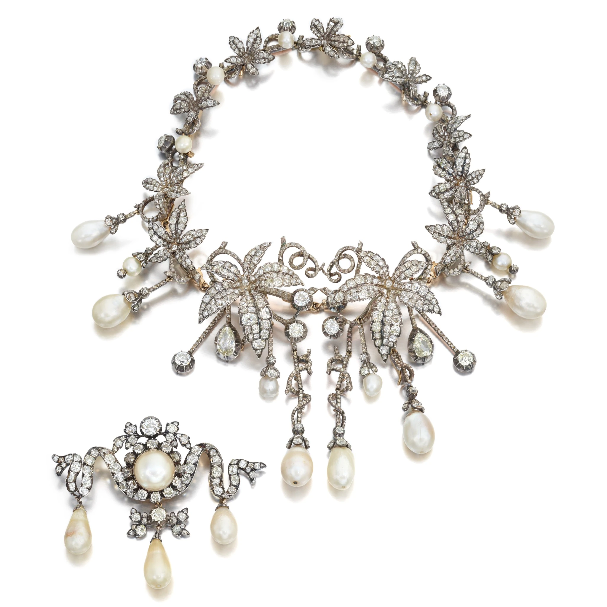 Collana e spilla con intricati disegni floreali e di foglie, che ricordano i diamanti di Napoleone, ornati da diamanti e grandi perle pendenti. La collana presenta una disposizione simmetrica con gocce di perle multiple.
