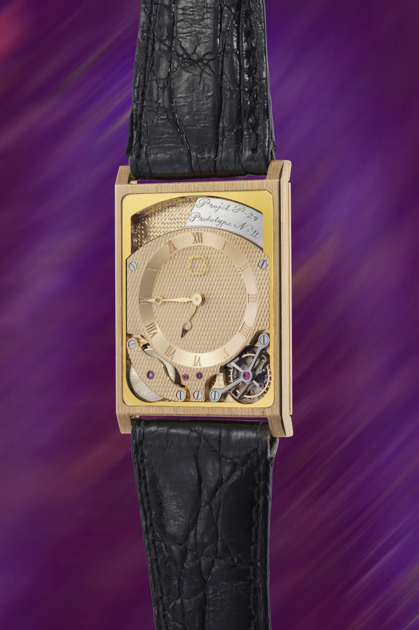 Orologio da polso rettangolare in oro della collezione Orologio, con quadrante testurizzato, numeri romani, movimento meccanico a vista e cinturino in pelle nera, su un vivace sfondo viola.