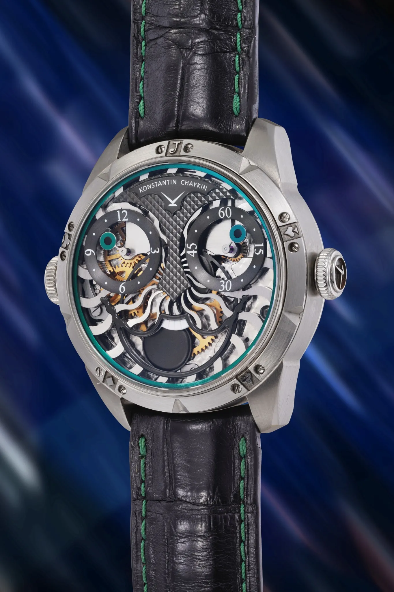 Orologio da polso meccanico della collezione orologio prototipo, con cinturino in pelle nera, quadrante traforato e accenti blu e verdi. Gli ingranaggi e i componenti visibili si stagliano su un suggestivo sfondo blu astratto.