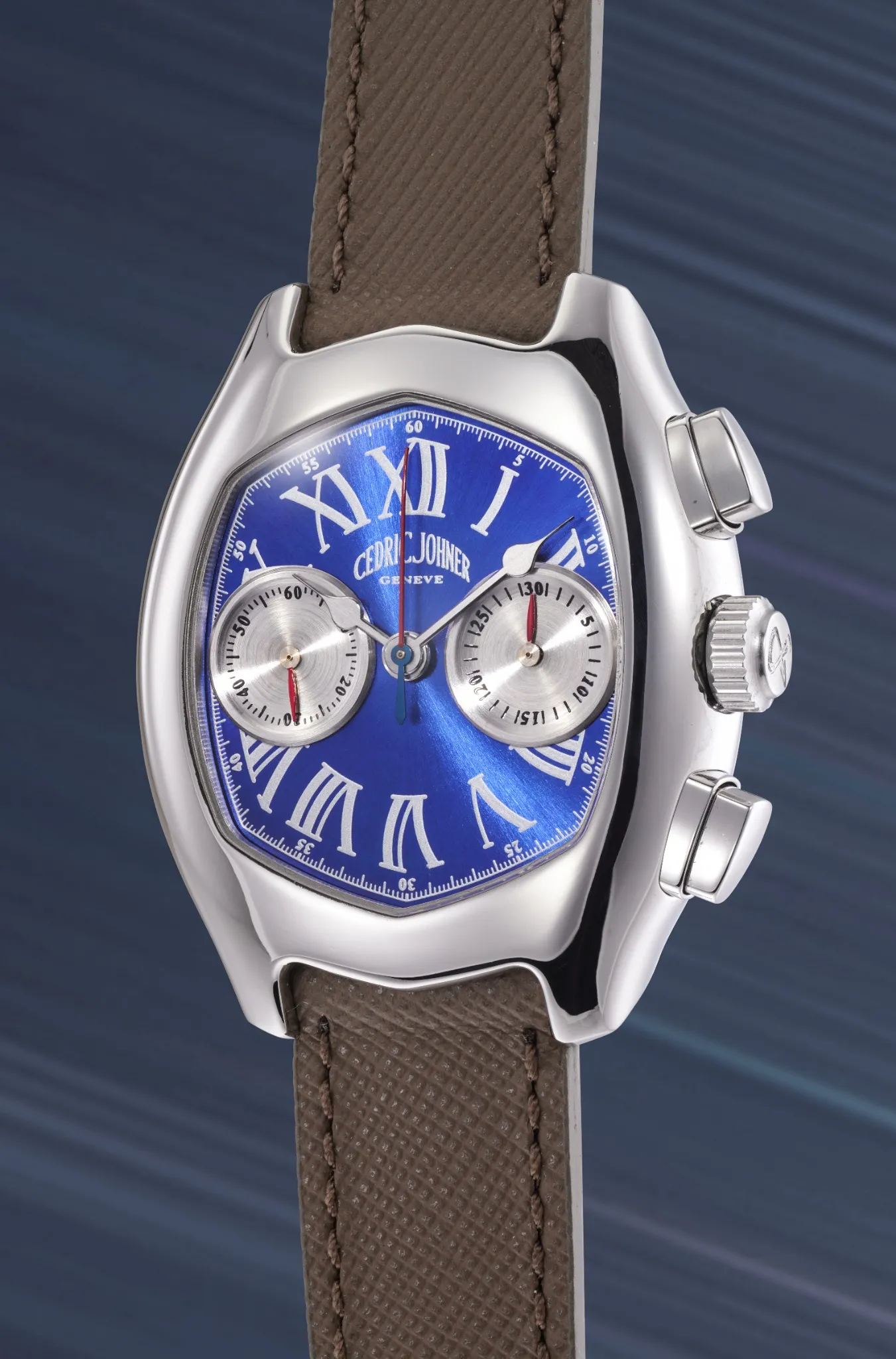 Orologio di lusso con quadrante blu, numeri romani argentati, due contatori, cinturino in pelle marrone testurizzata e cassa argentata lucida su sfondo blu sfumato.