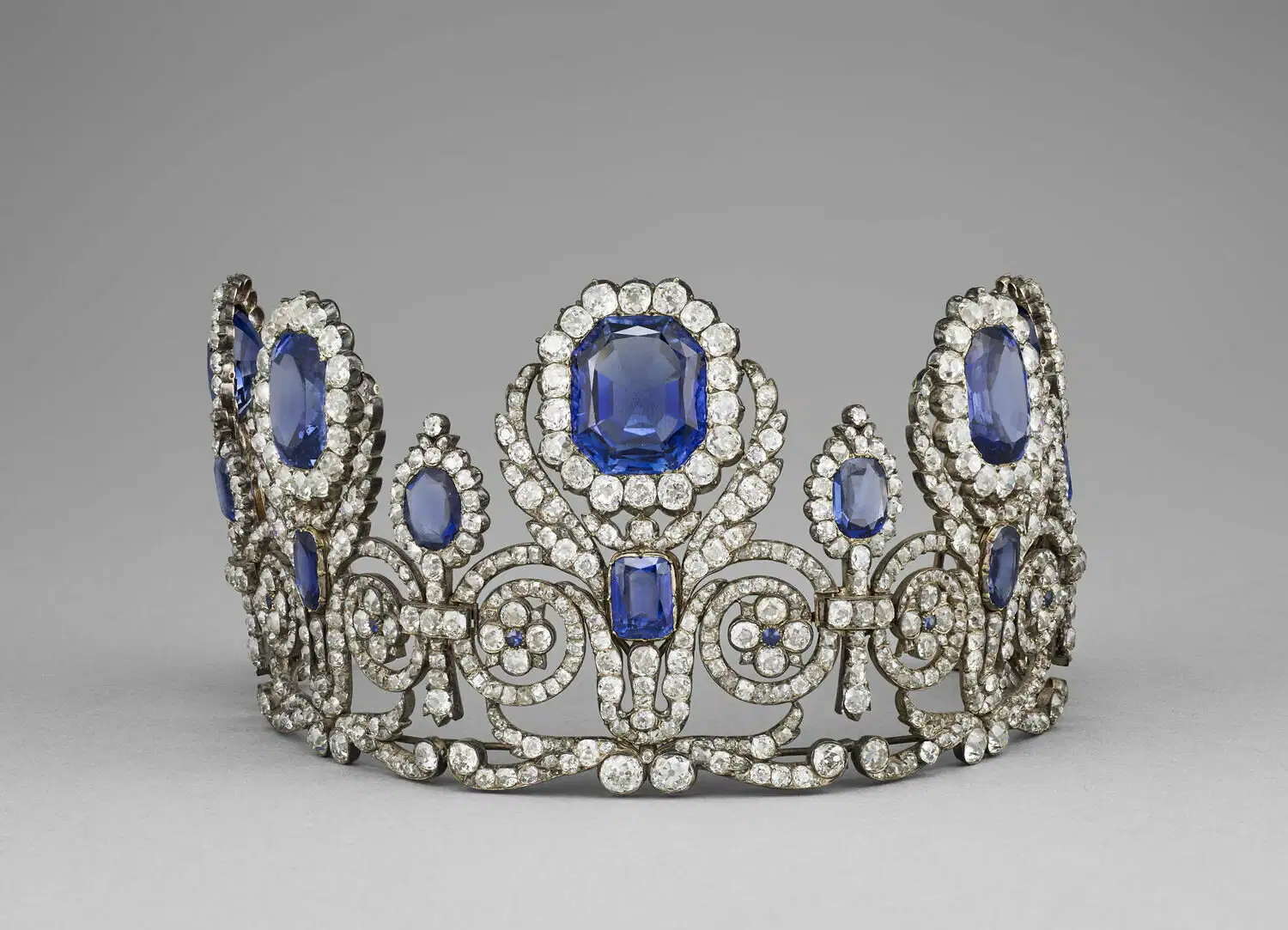 Un diadema di diamanti e zaffiri con grandi zaffiri blu circondati da diamanti scintillanti in un'intricata montatura d'argento, che evoca il fascino dei tesori perduti nel furto gioielli del Louvre.