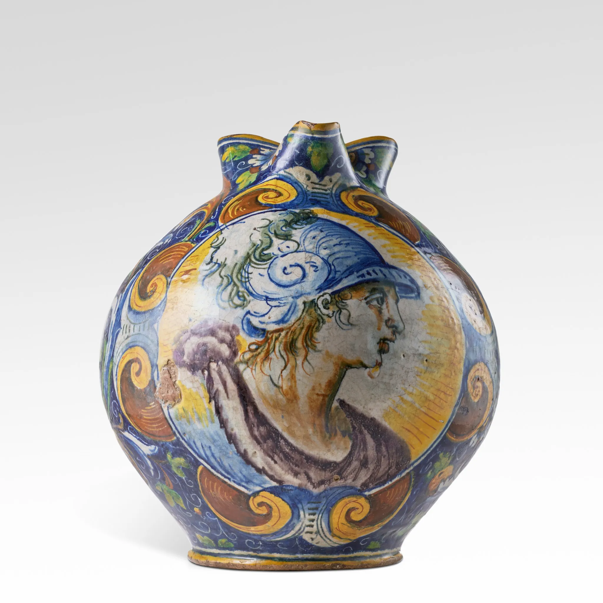 Brocca rotonda e ornata in ceramica a tre beccucci, decorata con motivi vorticosi e con il profilo dipinto di una figura che indossa un elmo blu, su uno sfondo giallo e blu - un pezzo che ricorda un record di Sotheby's Italia.