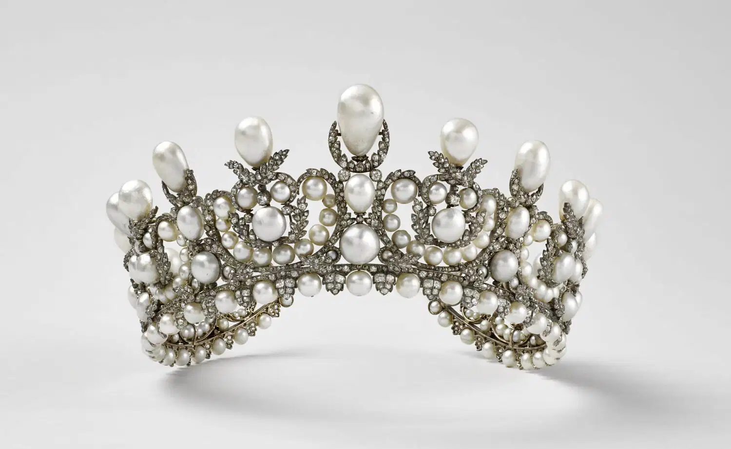 Un diadema regale ornato di perle grandi e piccole e diamanti scintillanti, disposti in un intricato motivo simmetrico con una perla centrale verticale, che ricorda i tesori perduti nel furto gioielli del Louvre, su uno sfondo chiaro.