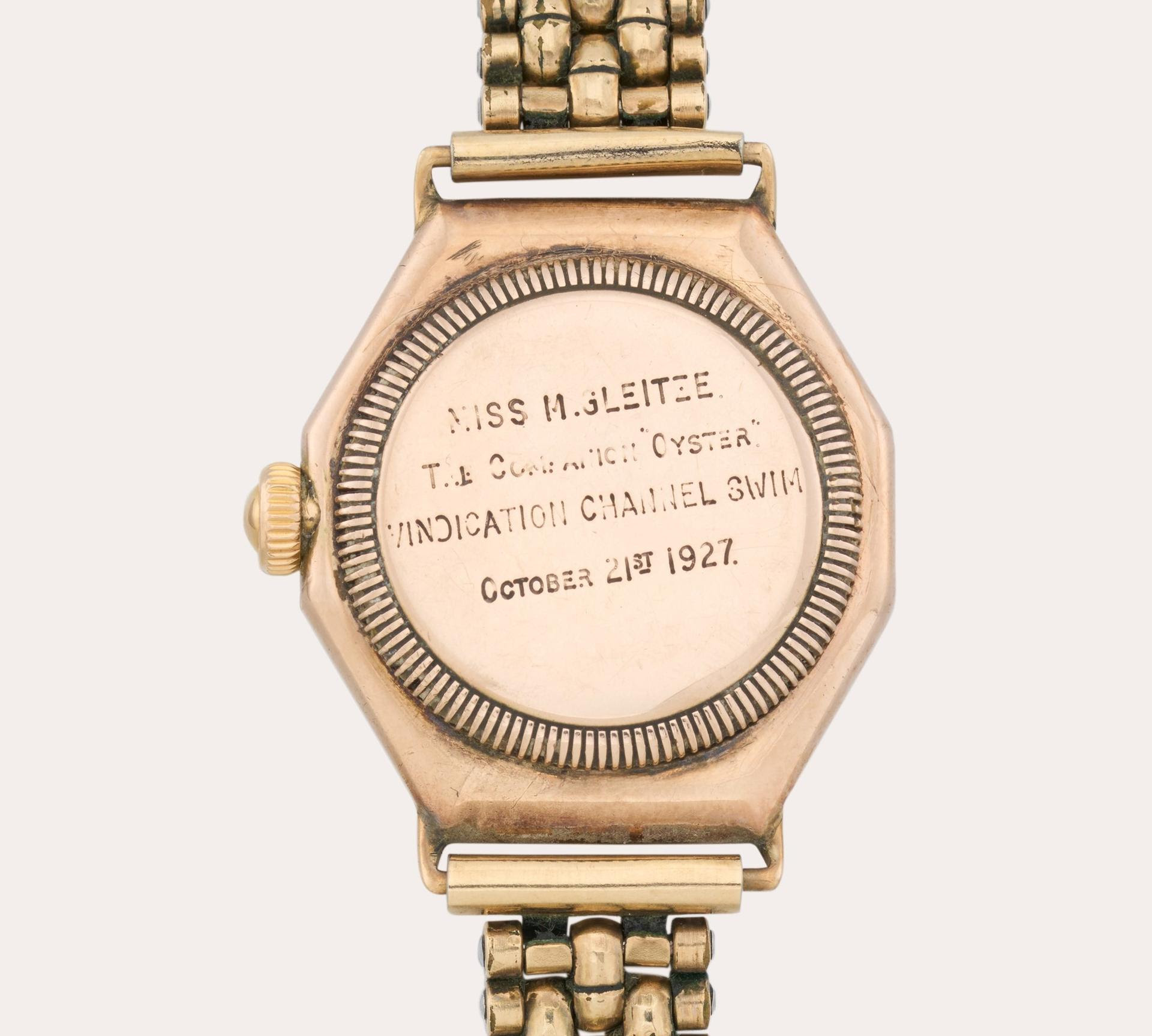Un orologio da polso in oro con il fondello inciso che recita: "MISS M. J. ELIETZE, THE ORIGINAL OYSTER, VINDICATION CHANNEL SWIM, OCTOBER 21ST 1927". Questo orologio a fascia in metallo ricorda Mercedes Gleitze e il suo iconico Rolex Channel Swim.