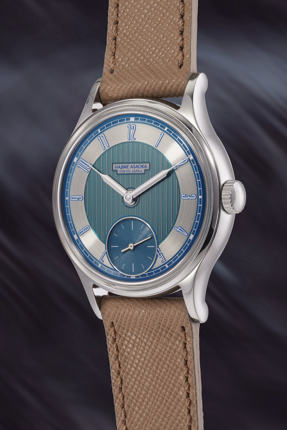 Orologio da polso ispirato agli orologi giapponesi, con quadrante azzurro e argento, quadrante dei piccoli secondi a ore 6 e cinturino in pelle marrone testurizzata, perfetto per ogni collezione lusso asta. Su uno sfondo scuro sfocato.