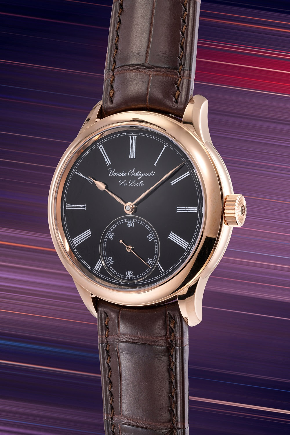 Orologio da polso di lusso orologi giapponesi con quadrante nero, indici a numeri romani, quadrantino dei piccoli secondi a ore 6, cassa in oro rosa e cinturino in pelle marrone, su uno sfondo striato e colorato.