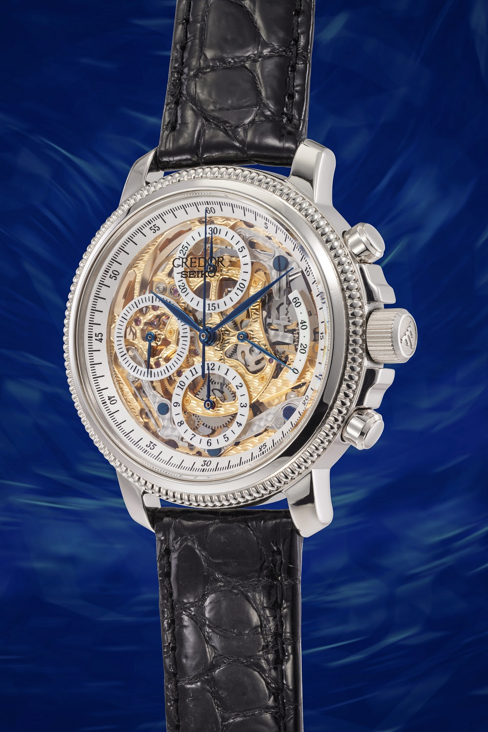 Un lussuoso orologio da polso con quadrante scheletrato e cinturino in pelle nera è esposto su un vorticoso sfondo blu, che ne mette in mostra gli intricati meccanismi interni e le funzioni cronografiche: uno squisito esempio di orologi giapponesi di lusso per un collezionista esigente ad un'asta.