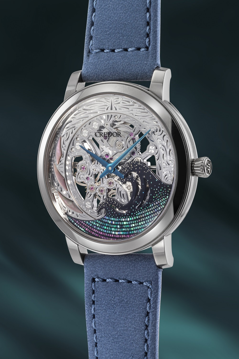 Un orologio scheletrato d'argento con intricate incisioni, lancette blu e dettagli in pietre preziose, incastonato in un cinturino di pelle blu, è visualizzato su uno sfondo scuro e delicatamente sfocato, che incarna la raffinatezza di orologi giapponesi lusso asta.