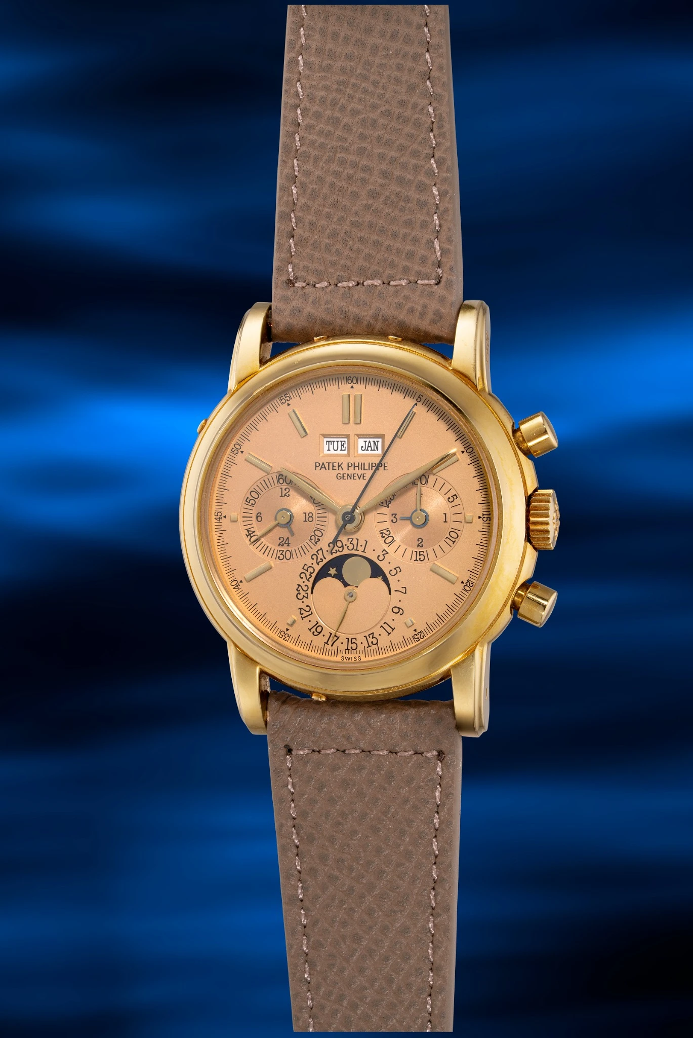 Orologio da polso Patek Philippe Hong Kong in oro con cinturino in pelle marrone, con indicatori del giorno, della data e del mese, contatori del cronografo e fasi lunari, su sfondo blu ondulato.