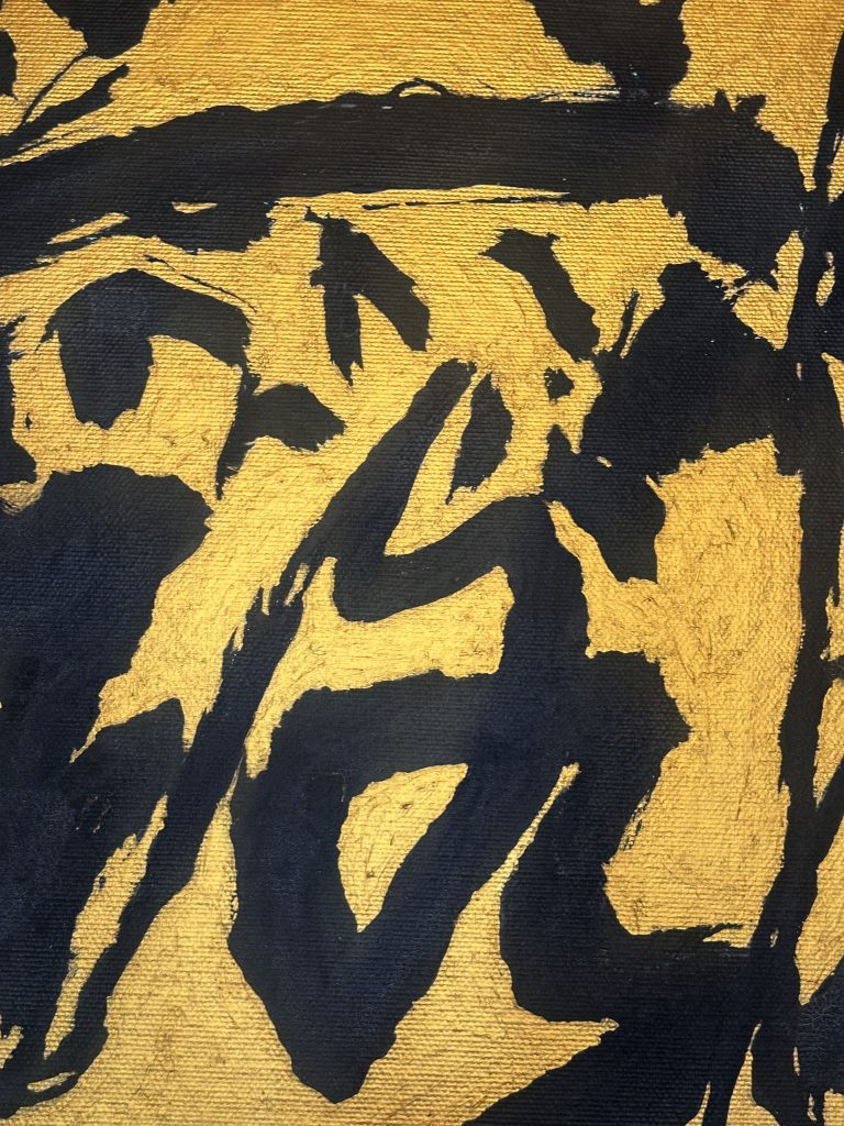 Pennellate nere, audaci e astratte su uno sfondo dorato e metallizzato, che ricorda una calligrafia espressiva o l'arte moderna. La composizione è dinamica, con linee ampie e angoli acuti.