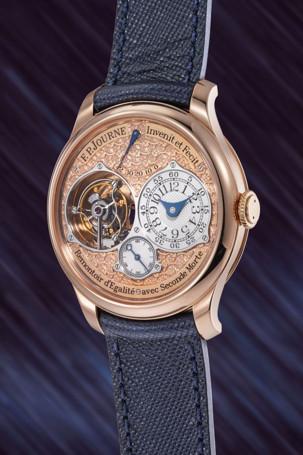 Un lussuoso orologio da polso F.P. Journe con cassa in oro rosa, intricato quadrante in rilievo, tourbillon a vista e cinturino in pelle testurizzata blu - una scelta eccezionale tra gli orologi costosi 2025 - incastonato su uno sfondo viola sfocato.