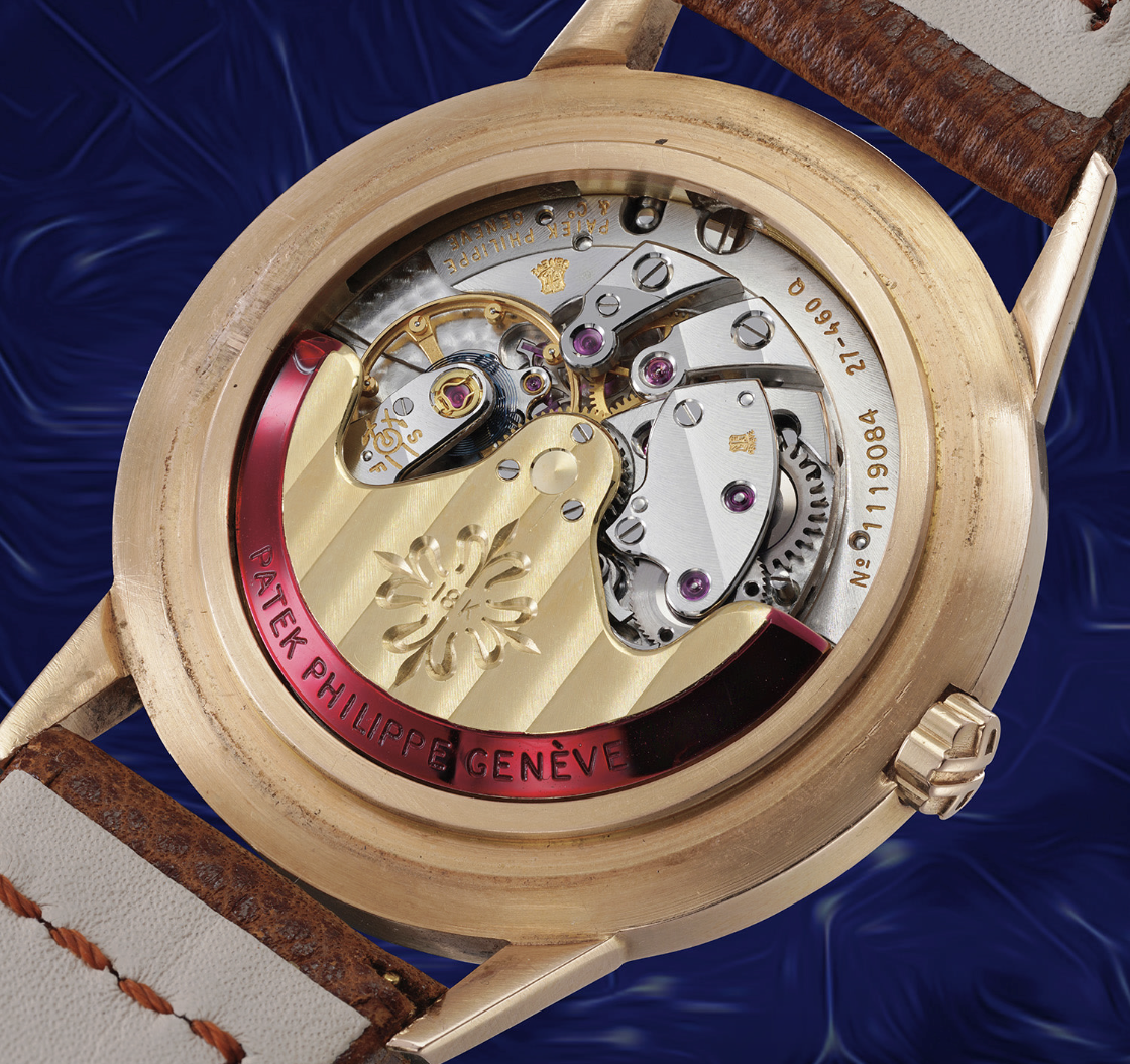 Primo piano dell'intricato movimento meccanico di un orologio da polso Patek Philippe, con ingranaggi, gioielli e incisioni visibili attraverso il fondello trasparente e il cinturino in pelle marrone, che spicca tra gli orologi costosi 2025.