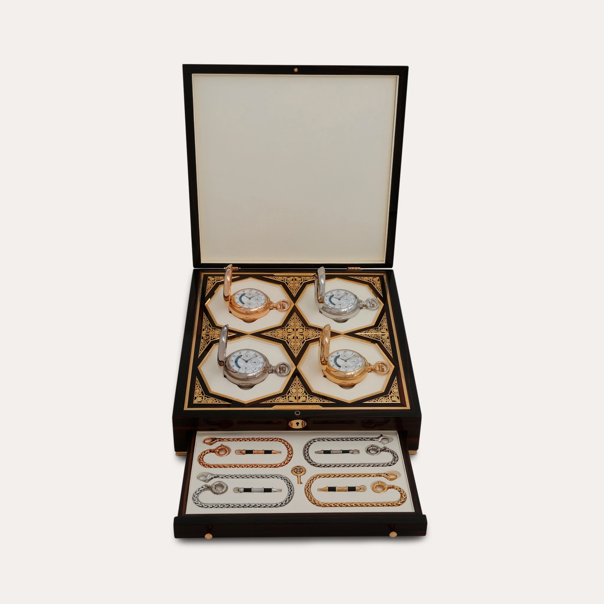 Una scatola ornata in nero e oro ispirata ad Abu Dhabi Lusso, con coperchio aperto, mostra quattro orologi da tasca decorativi e un cassetto estraibile contenente diverse catene eleganti disposte ordinatamente.