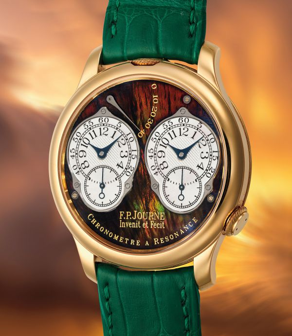Orologio di lusso F.P. Journe con cassa in oro, cinturino in pelle verde e doppio quadrante bianco. Il quadrante presenta dettagli intricati e la scritta del marchio, su uno sfondo caldo e sfocato.