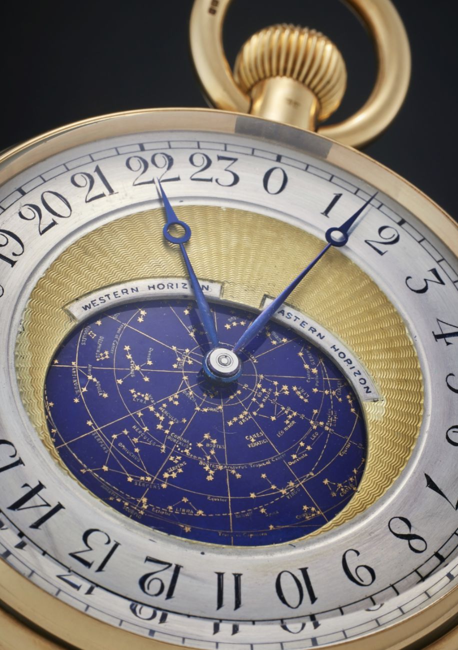 Primo piano di un orologio da tasca in oro - uno degli orologi costosi 2025 - caratterizzato da una mappa stellare al centro, dettagli celestiali blu e oro, numeri romani e una corona di carica ornata nella parte superiore.