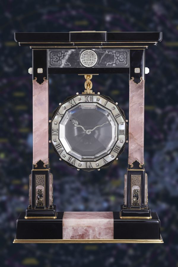 Orologio da camino in stile Art Déco con colonne in marmo rosa e nero, accenti decorativi in argento e quadrante rotondo sospeso da una catena d'oro, su uno sfondo scuro e astratto.