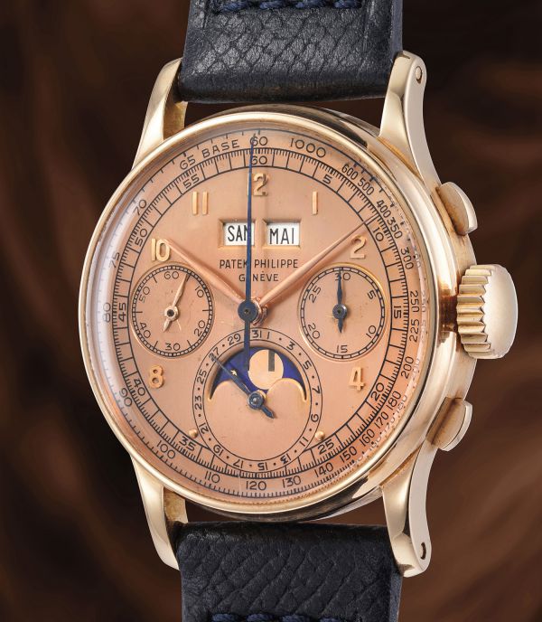 Primo piano di un orologio da polso Patek Philippe vintage con cassa in oro, cinturino in pelle, tre contatori e indicazione delle fasi lunari. Il quadrante presenta le indicazioni del giorno, del mese e del tachimetro.